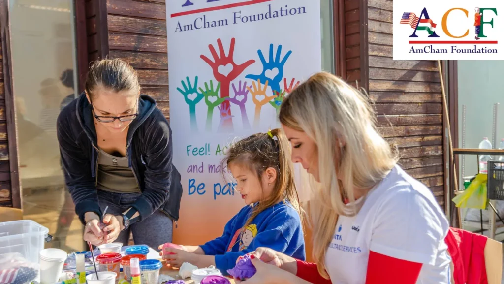 AmCham alapítvány által szerveztt kreatív program. Egy kislány gyurmázik két fiatal nő társaságában.
